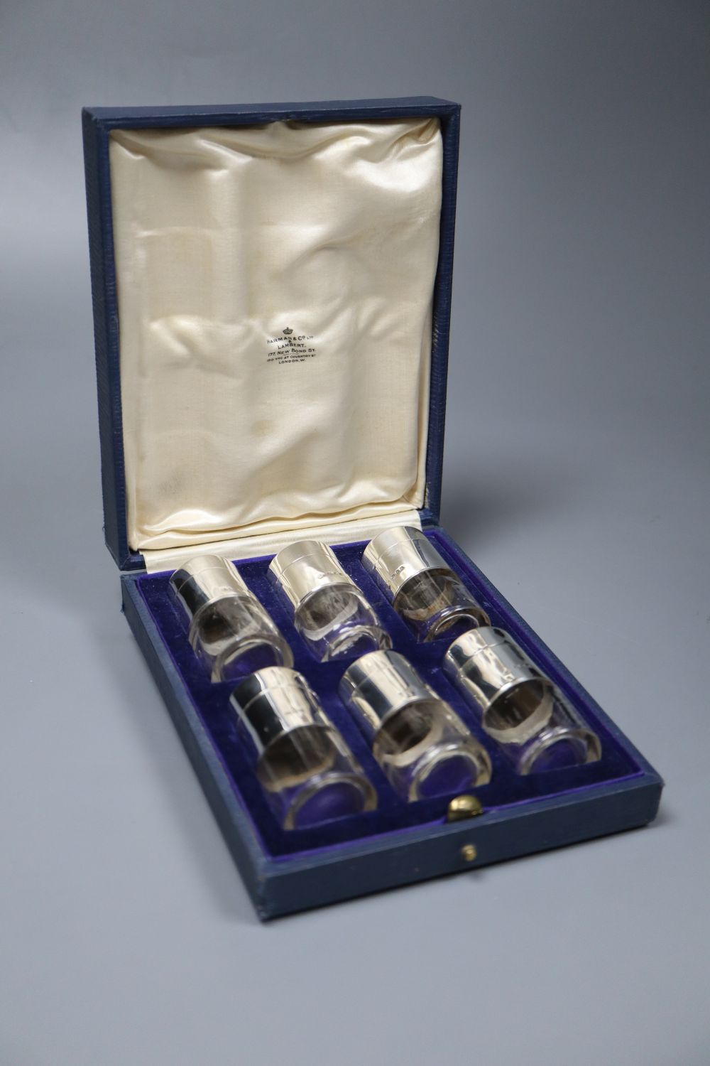 A cased set of six George V silver mounted cylindrical glass pepperettes, Harman & Co, London, 1928, 65mm.